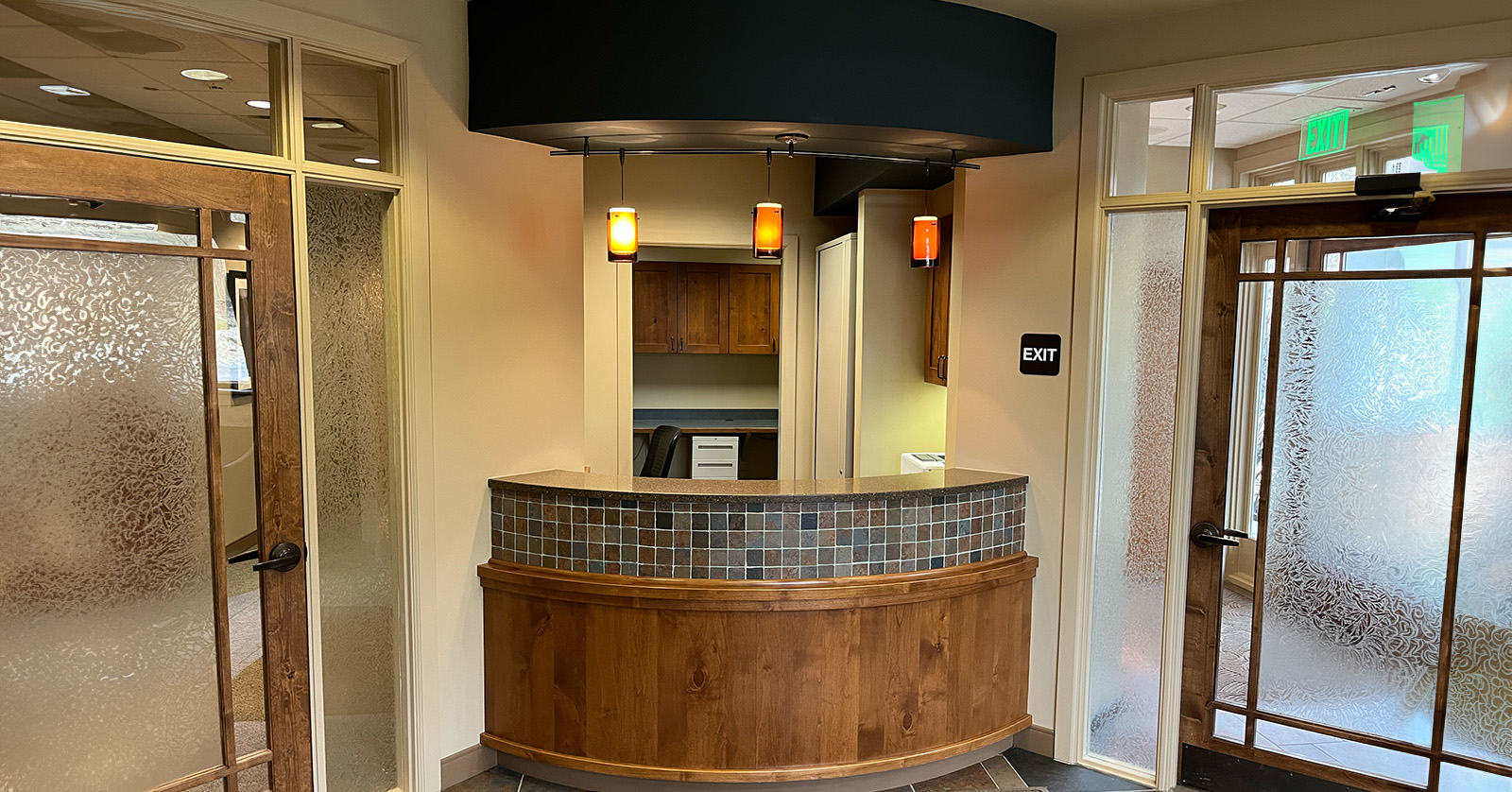 An interior view of a lobby with a counter, a sign above it, and a door in the background.